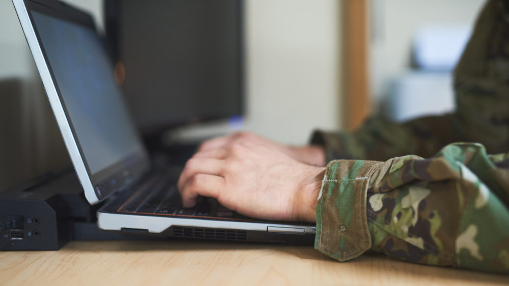 Cropped shot of a soldier using a laptop in the dorms of a military academy