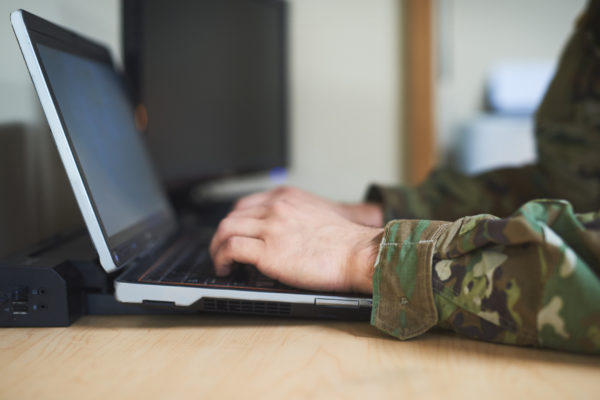 Cropped shot of a soldier using a laptop in the dorms of a military academy